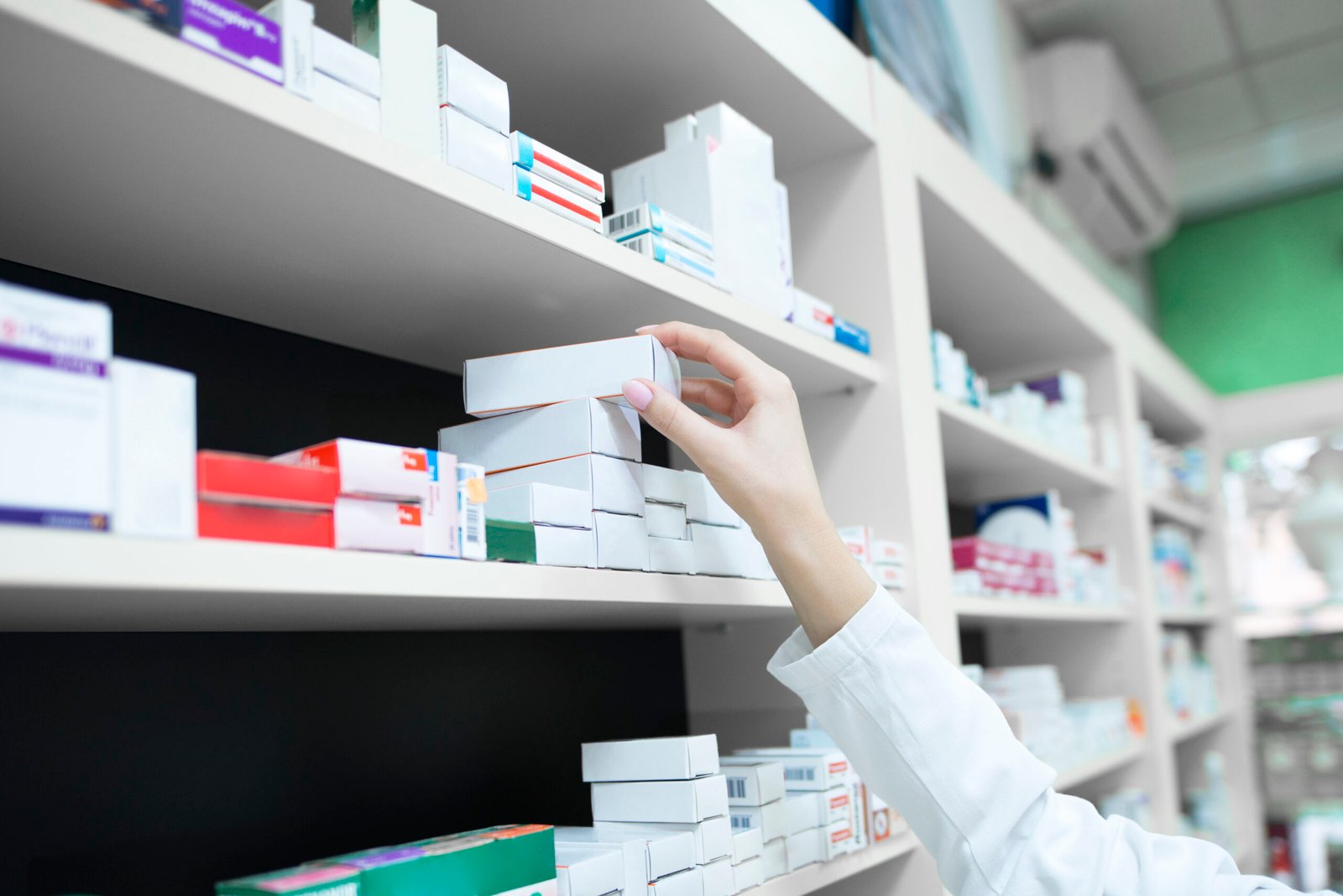 Farmacéutica cogiendo una caja de una estantería